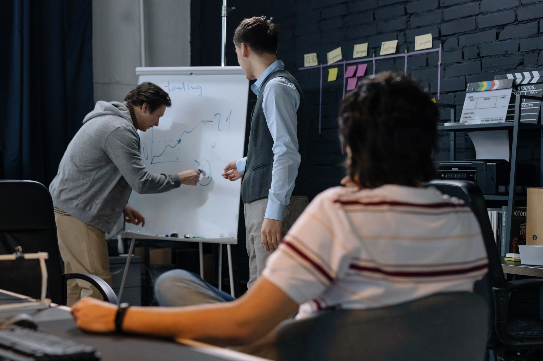 Business team brainstorming and discussing strategy at a whiteboard in a startup office
